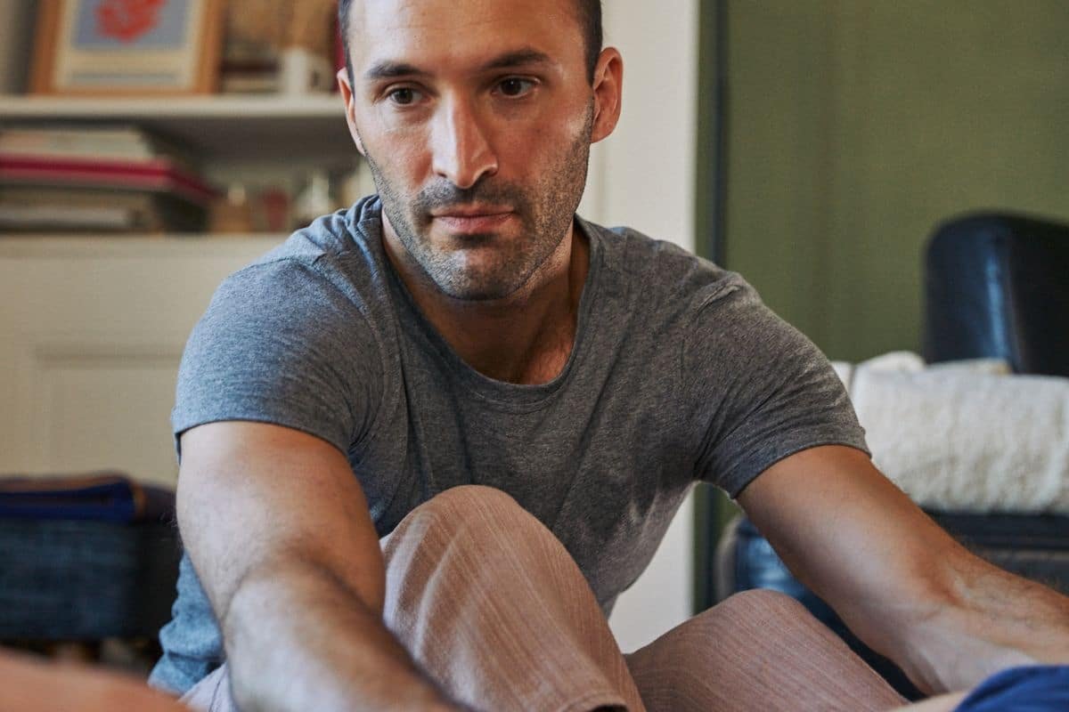Nicolas Luc Levé sitting on the floor in a slow, focused stretch